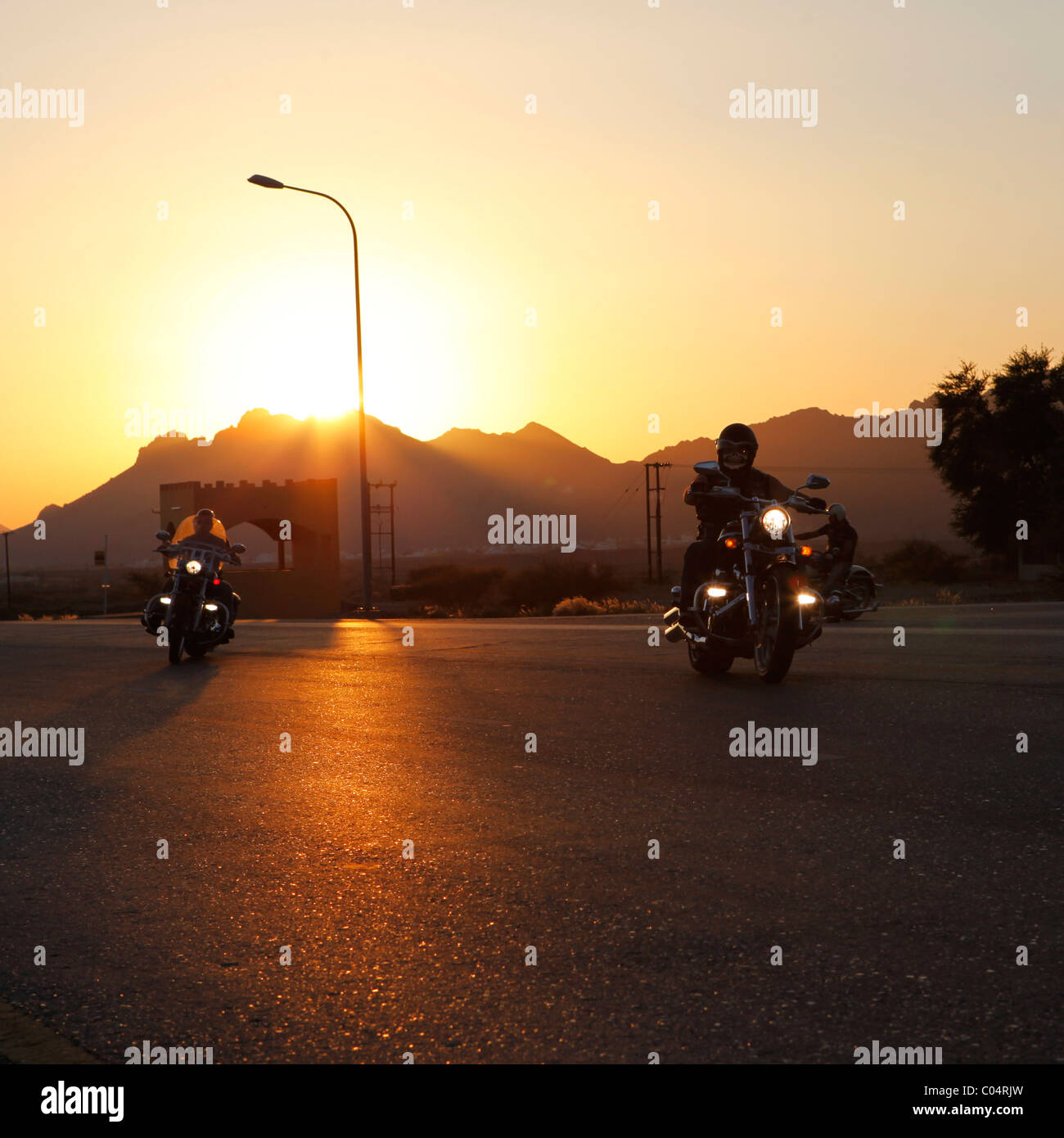 Eine Gruppe von Harley-Davidson Biker fährt in die Wüste als die Sonne untergeht. Stockfoto