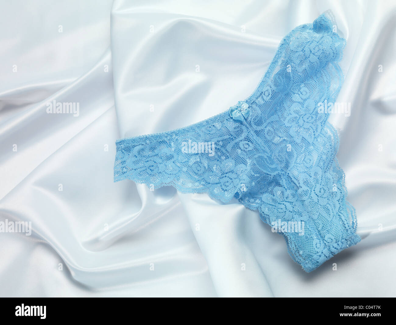 Blaue Spitzenunterwäsche auf glänzenden weißen seidigen Stoff Stockfoto