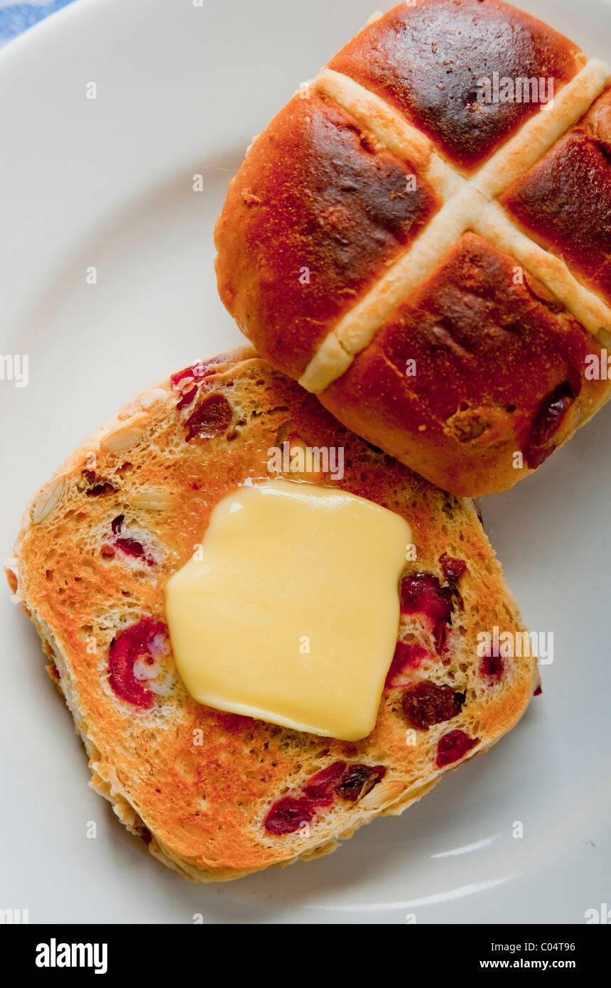 Ostern mit Butter Hot Cross Buns auf weißen Teller mit Narzissen Serviette auf Tischdecke Stockfoto