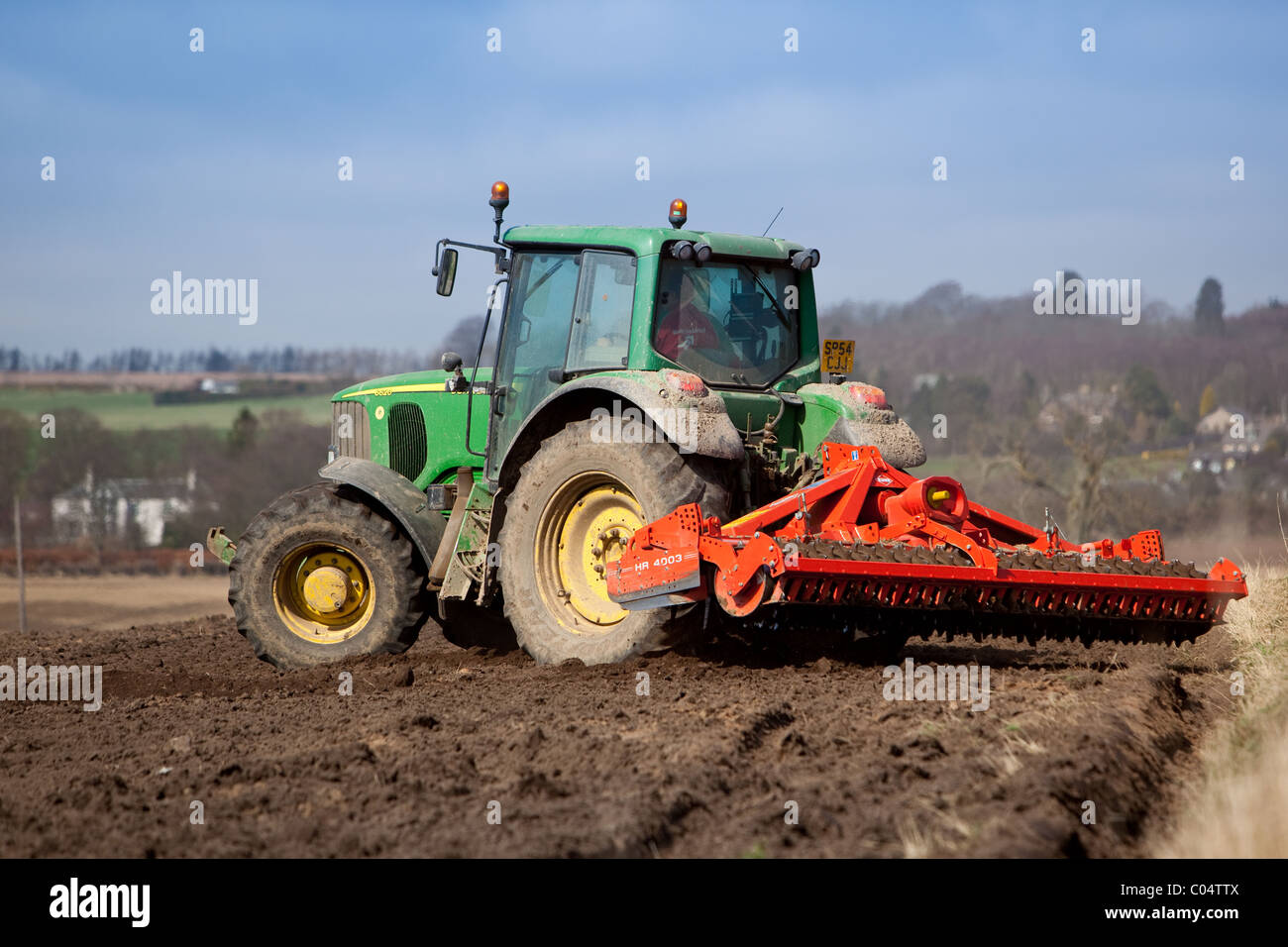 Traktor Eggen Feld nach dem Pflügen in Vorbereitung für die Aussaat von Frühling. Stockfoto