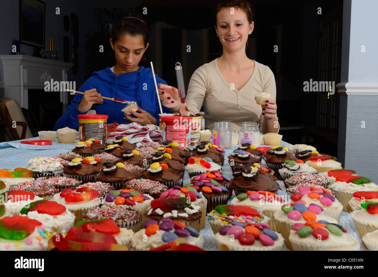 Zwei Mädchen im Teenager-Alter home Dekoration gemacht Cupcakes auf einen Tisch für eine große Partei Stockfoto
