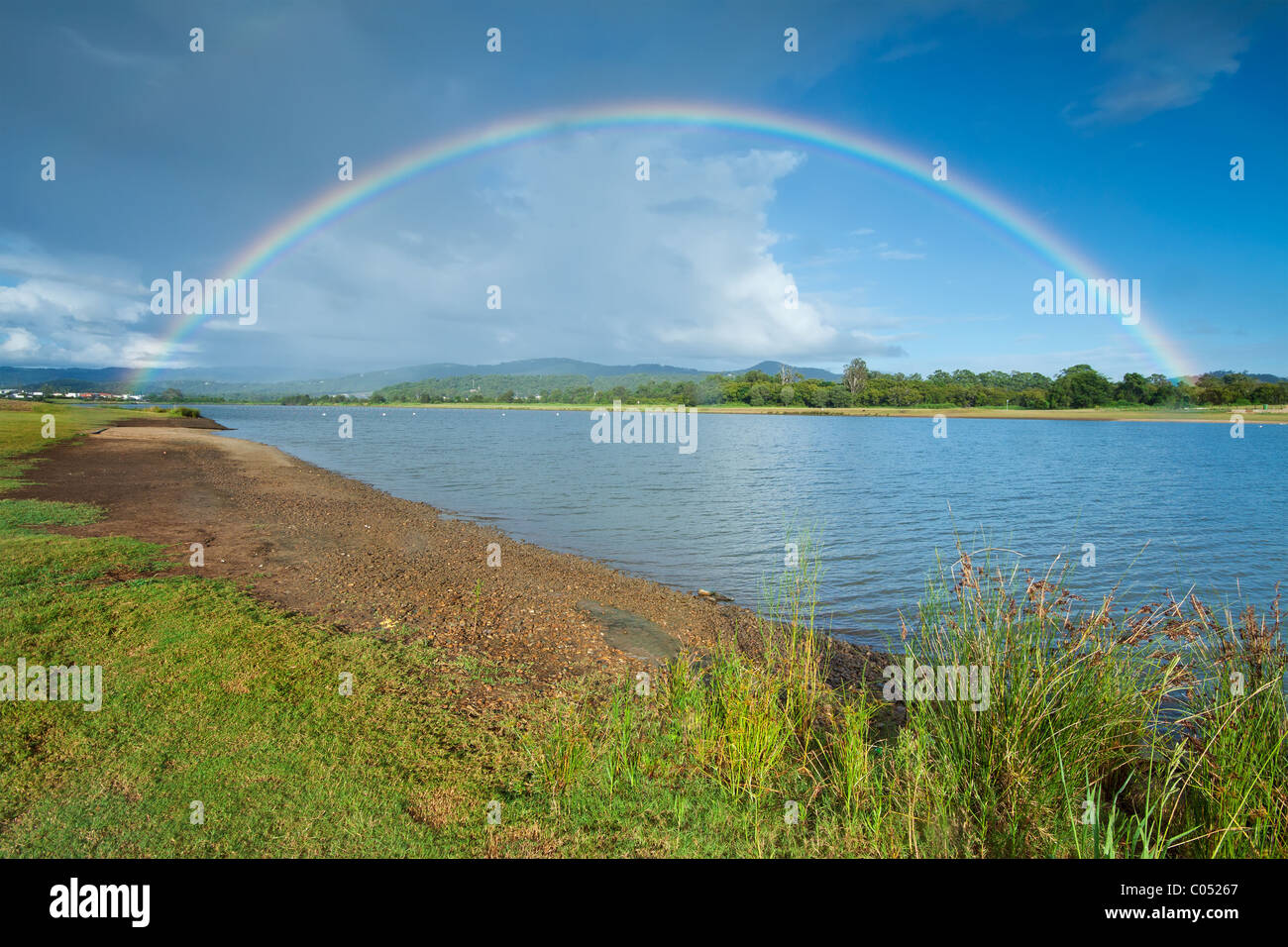 Morgen Regenbogen auf bewölkter Himmel mit See im Vordergrund (upper Coomera, Qld, Australien) Stockfoto