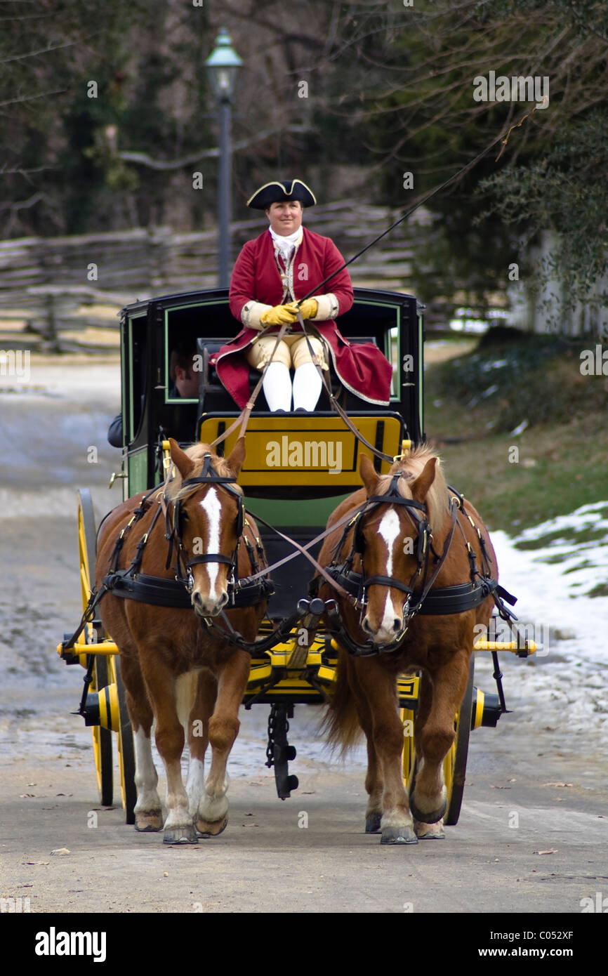 Ein Kutscher fährt ein Pferd und Wagen auf einer verschneiten Straße im historischen Colonial Williamsburg, VA. Stockfoto