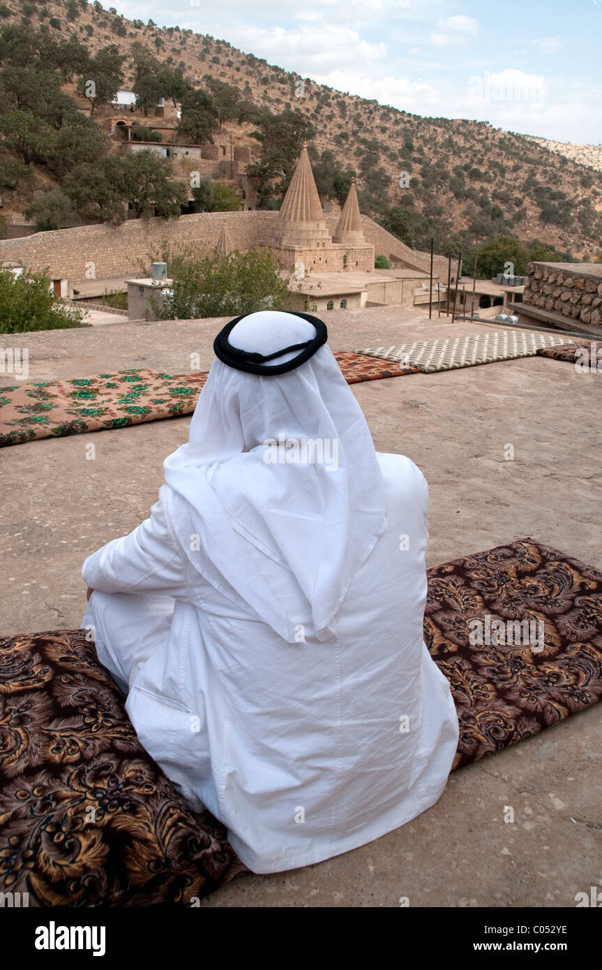 Eine Anbeterin sitzt mit Blick auf den Tempel des Heiligen Yeziden religiöse Stätte von Lalish, in der Region Kurdistan im Nordirak. Stockfoto