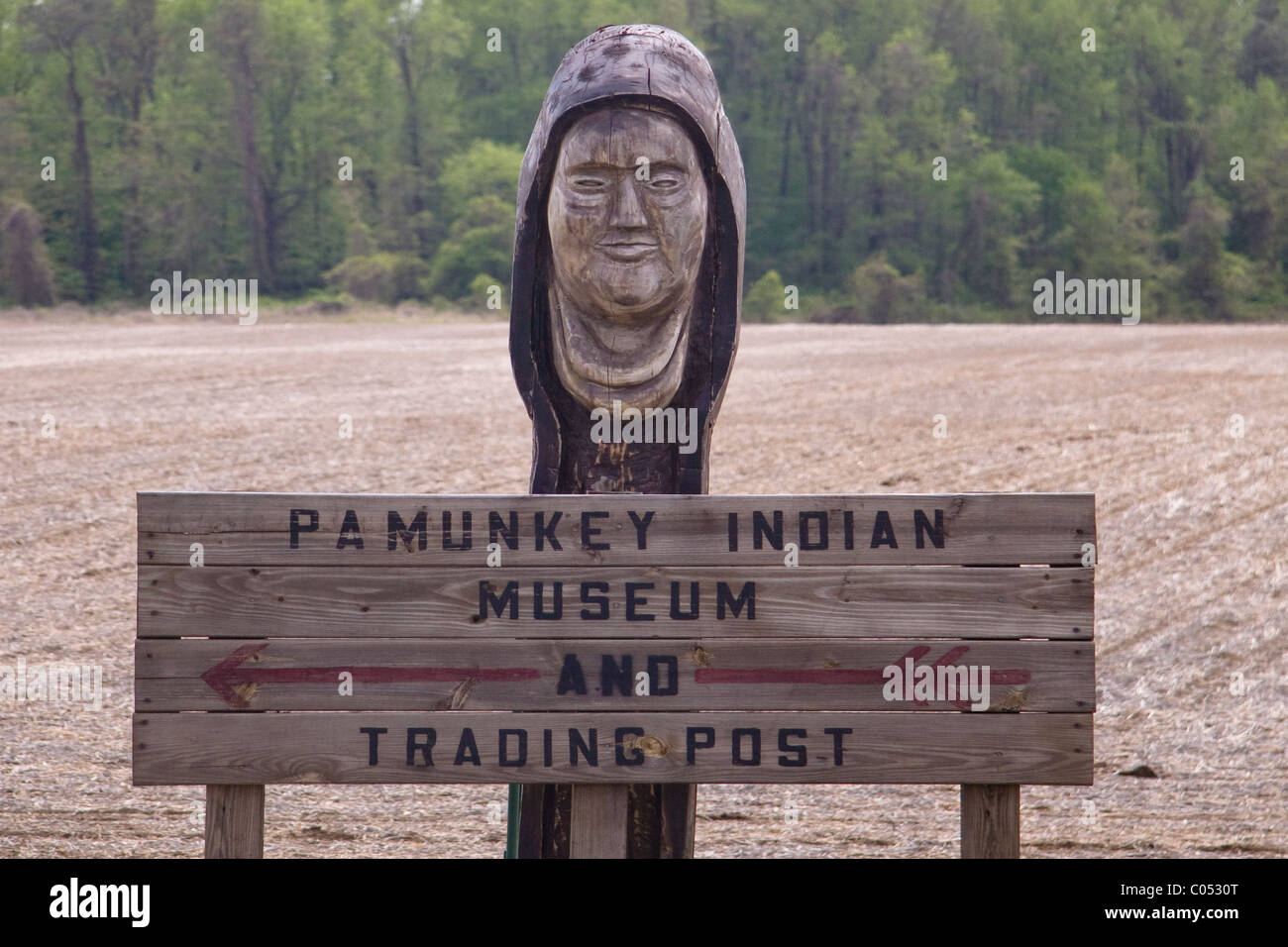 Hölzerne Totempfahl und Pamunkey Indian Museum und Handelsposten Richtungsanzeiger in der Nähe eines gepflügten Felds bei ihrer Reservierung in VA. Stockfoto