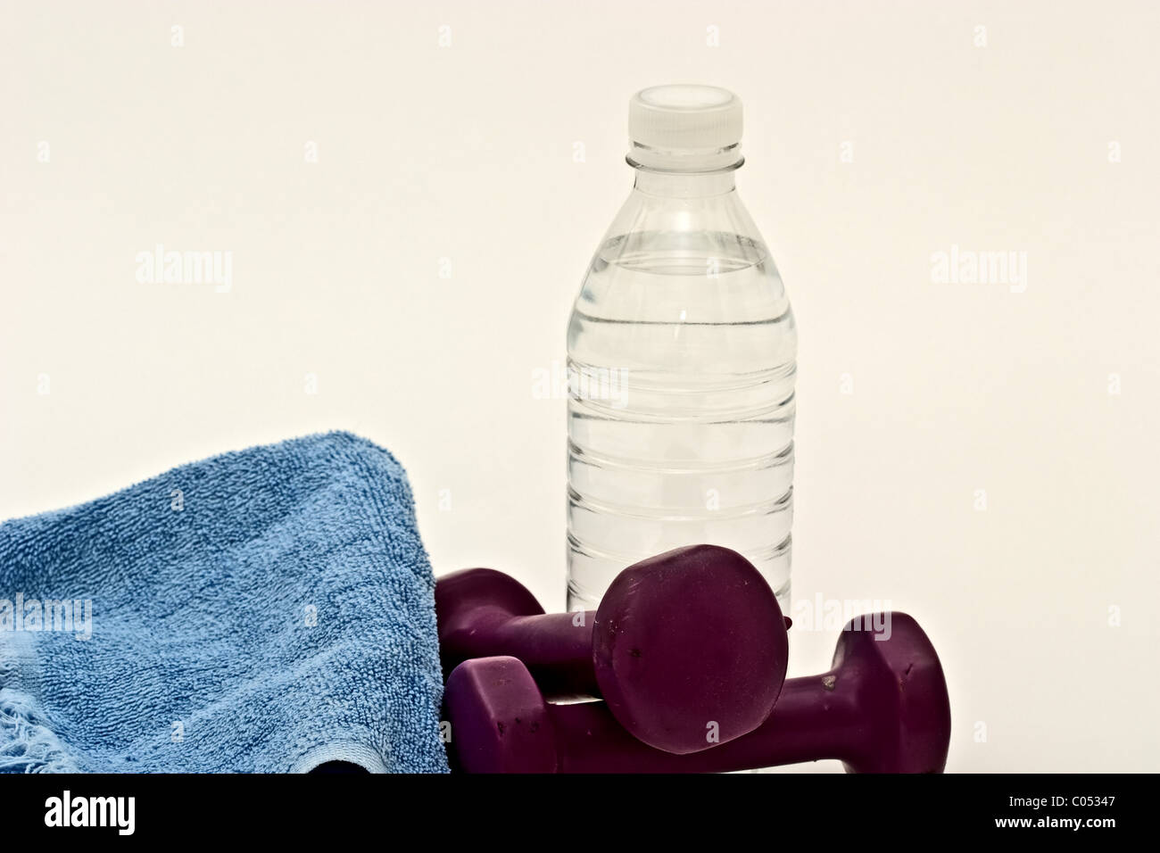 Eine Hantel auf einem Schweiß-Handtuch neben einer Flasche Wasser Stockfoto