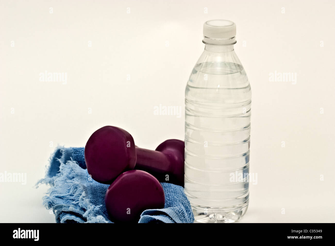 Eine Hantel auf einem Schweiß-Handtuch neben einer Flasche Wasser Stockfoto