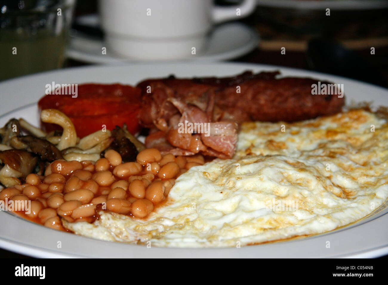 Englisches Frühstück bestehend aus Würstchen, gebackene Bohnen, gebratene Tomaten und Speck Stockfoto