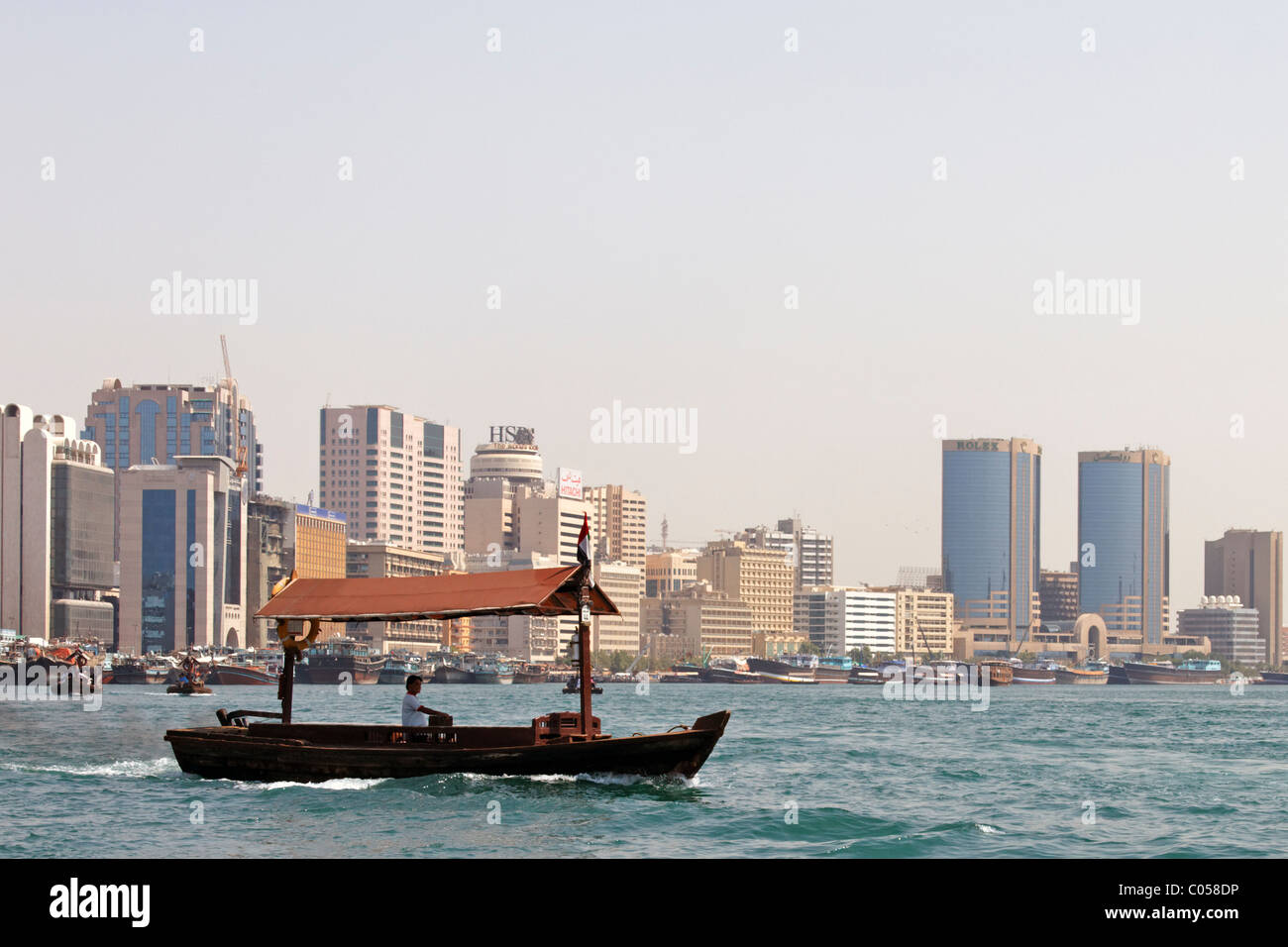 Traditionellen Fähre Überquerung des Baches vor dem Hintergrund der festgemachten Dhaus und modernen Dubai Stockfoto