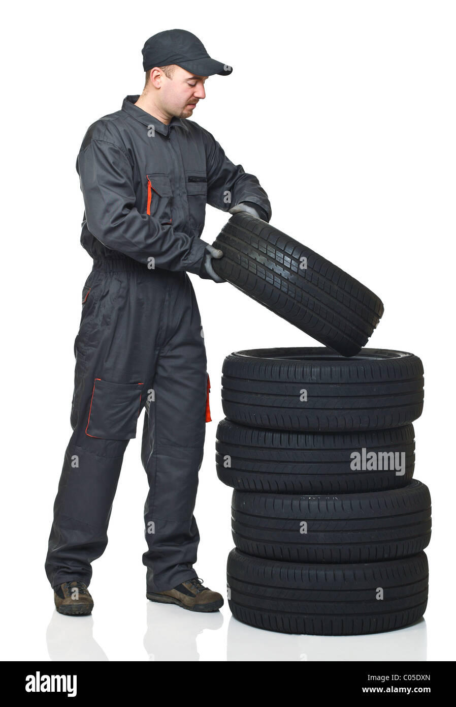 junge Mechaniker bewegen Reifen isoliert auf weißem Hintergrund Stockfoto