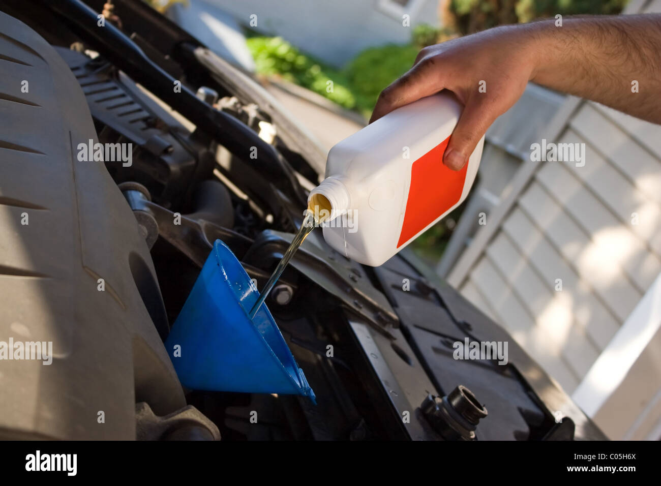 Die Hand eines Hinterhof-Mechanikers Gießen eine Flasche Motoröl in einem Motor während eines Öls verändern Wartung. Stockfoto