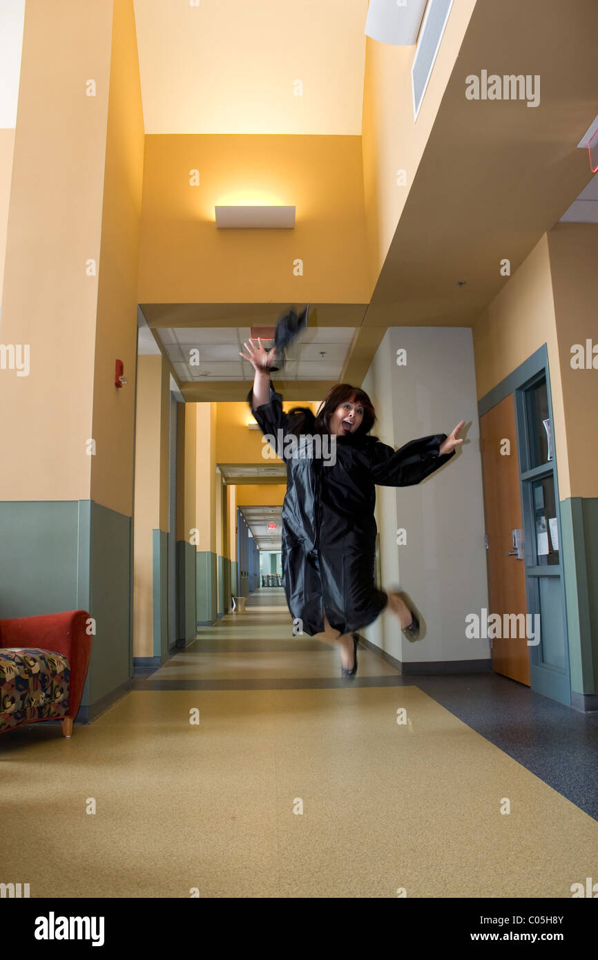 Eine junge Hispanic Frau springt in die Luft mit Freude beim tragen ihre Mütze und Mantel. Leichte Bewegungsunschärfe an Händen und Füßen. Stockfoto