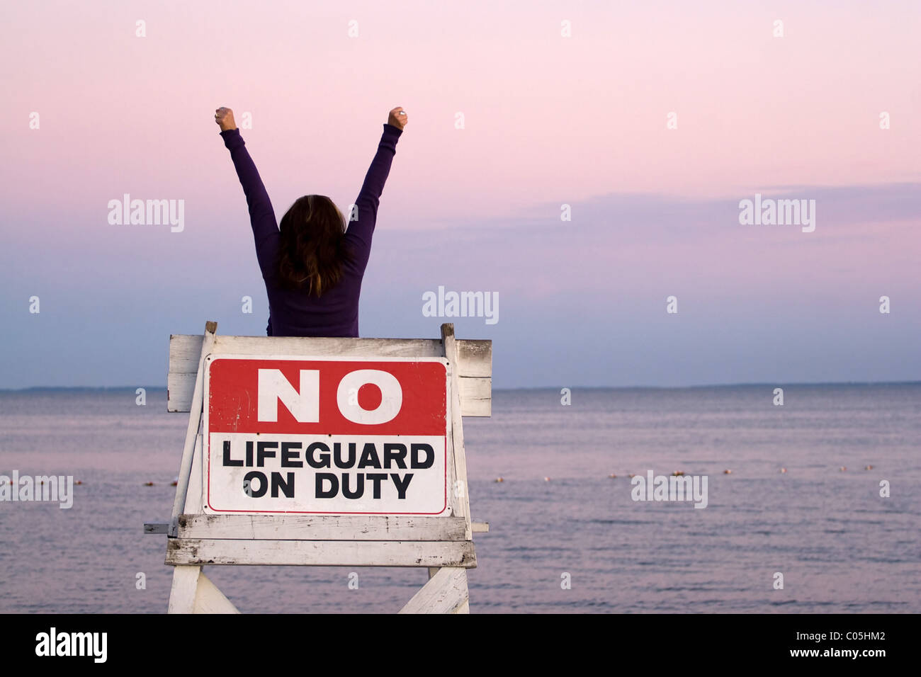 Eine Frau hält ihre Arme in der Luft sitzen auf einem Stuhl frei Rettungsschwimmer am Strand. Stockfoto