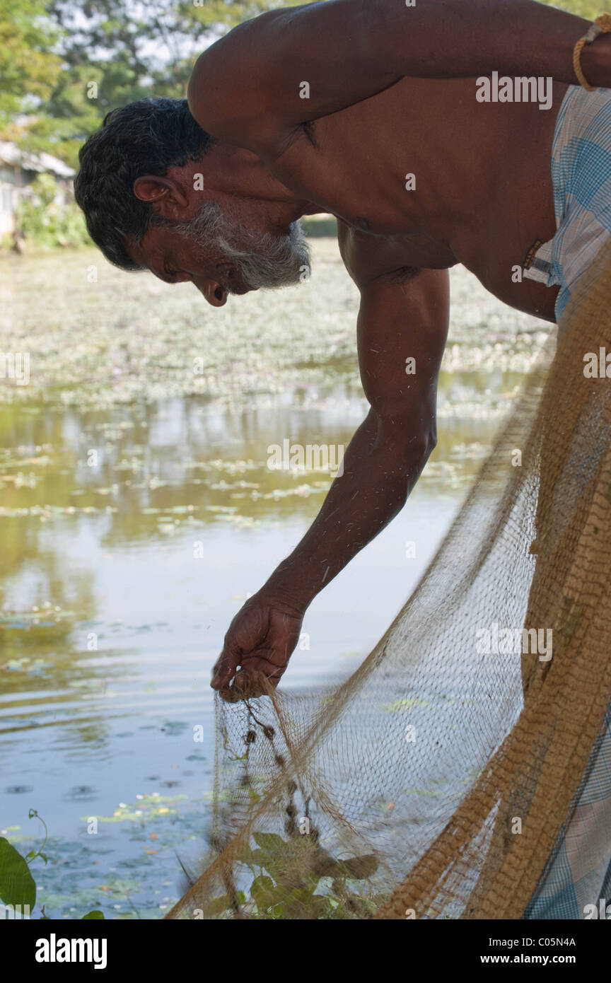 Ein Bangladeshi Fischer, Angeln in der traditionellen Weise, das Fischernetz aus dem Wasser ziehen Stockfoto