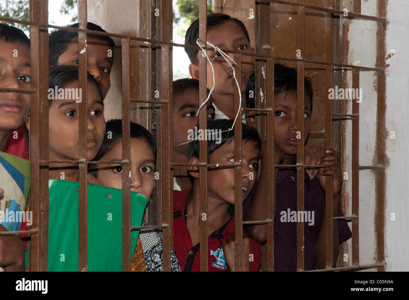 Eine Gruppe von Schulkindern aus Bangladesch Blick durch die Gitterstäbe im Fenster der Schule Stockfoto