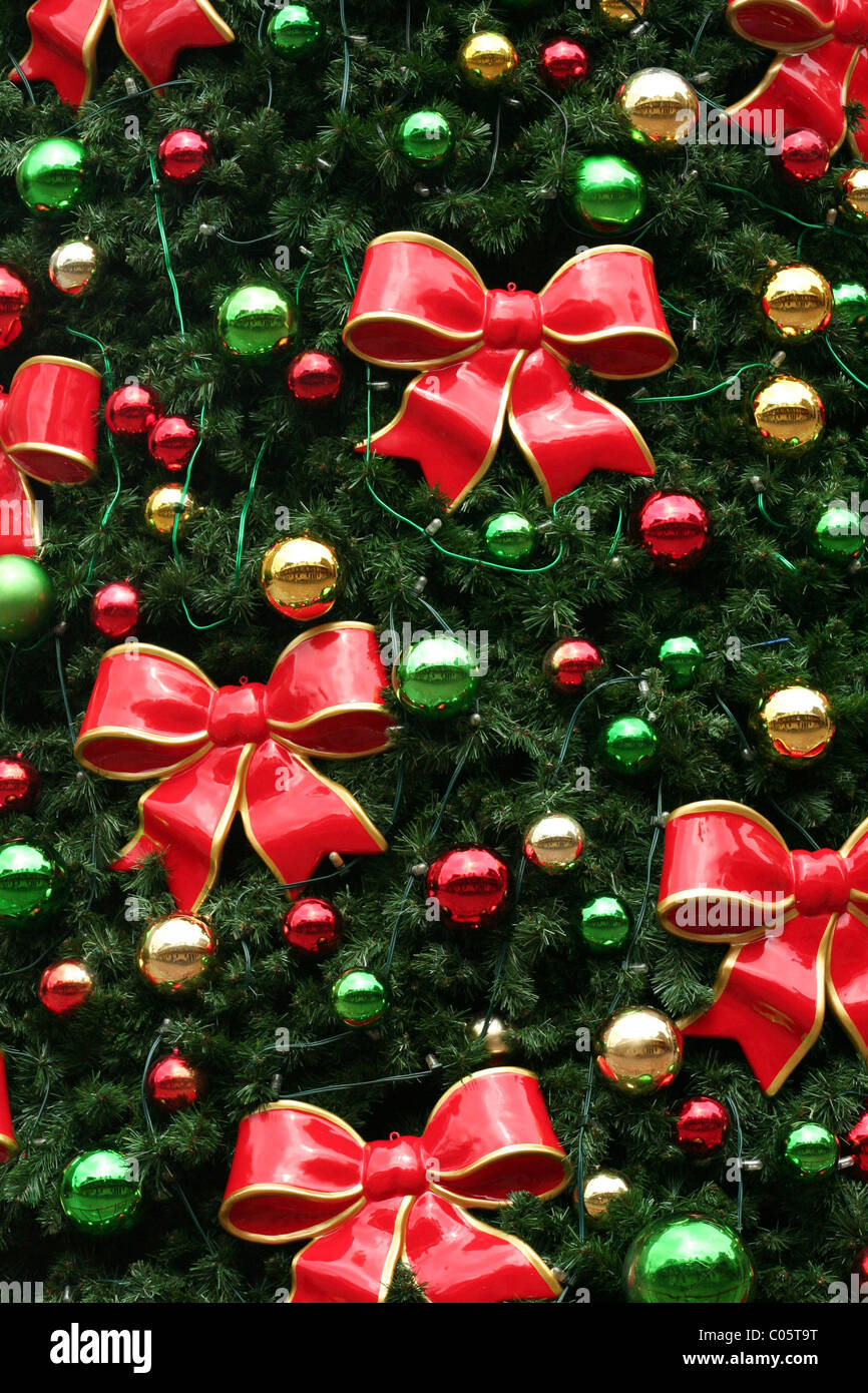 ROTE, MIT GOLD UMRANDETE SCHLEIFEN UND FARBIGE KUGELN SCHMÜCKEN EINEN WEIHNACHTSBAUM Stockfoto