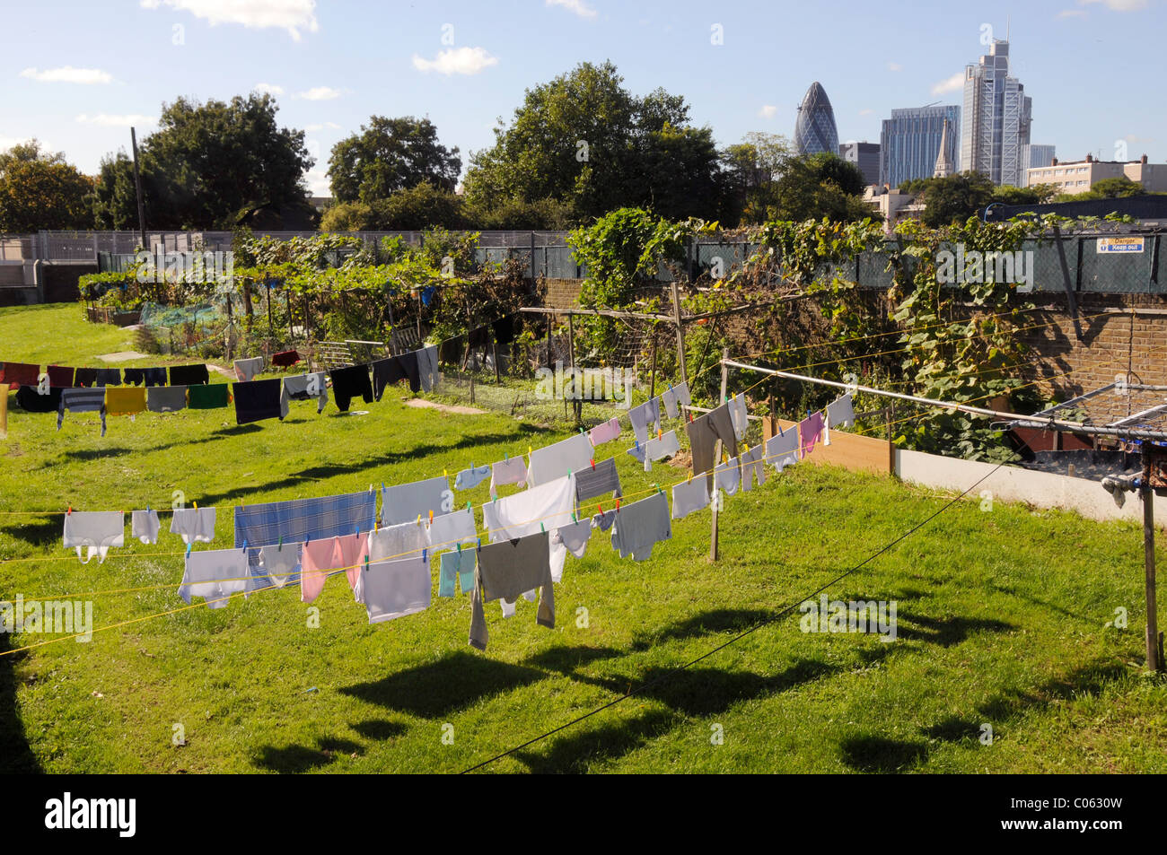 VEREINIGTES KÖNIGREICH. Kleider zu trocknen in der Sonne in einem Garten in der Nähe von Spitalfields City Farm, mit Blick auf die Stadt im Hintergrund, in Ost-London Stockfoto