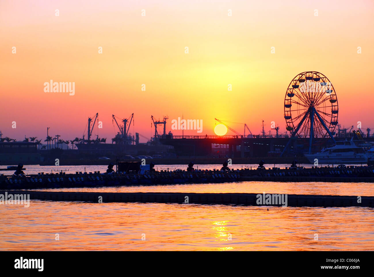 Einen wunderschönen Sonnenuntergang über Kaohsiung Hafen mit Kränen und ein Riesenrad Stockfoto