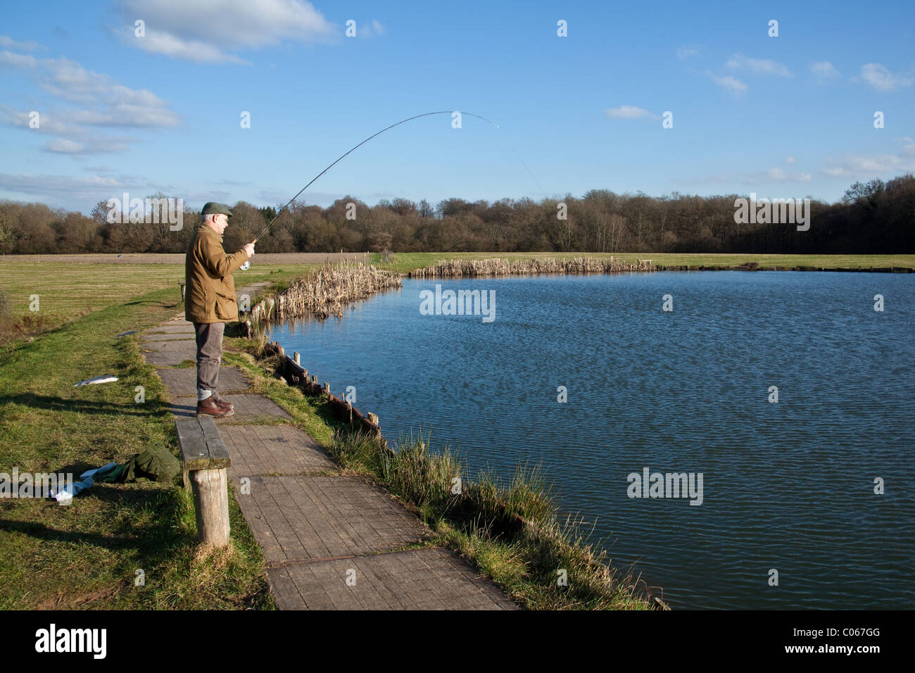 Fliegen Sie Fischer fangen einen Fisch in der Blackwool Farm-Forellen-Fischerei in West Sussex, England, Vereinigtes Königreich. Stockfoto