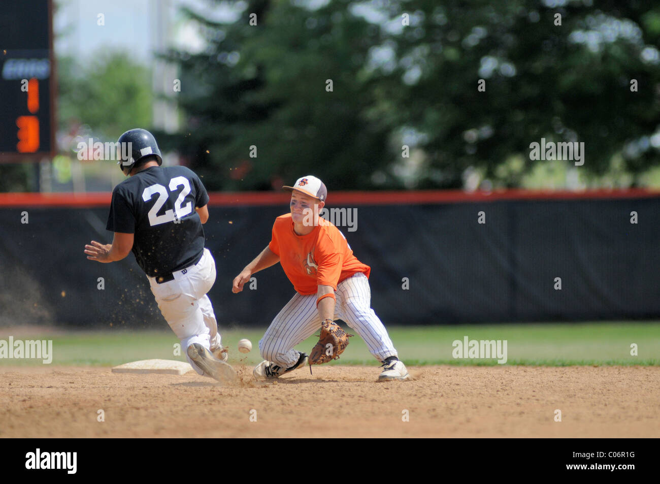 Shortstop zur ersten Base Seite der zweiten Base sichert werfen, um eine gleitende Base Runner High School Baseball Spiel, in den Ruhestand zu treten. USA. Stockfoto
