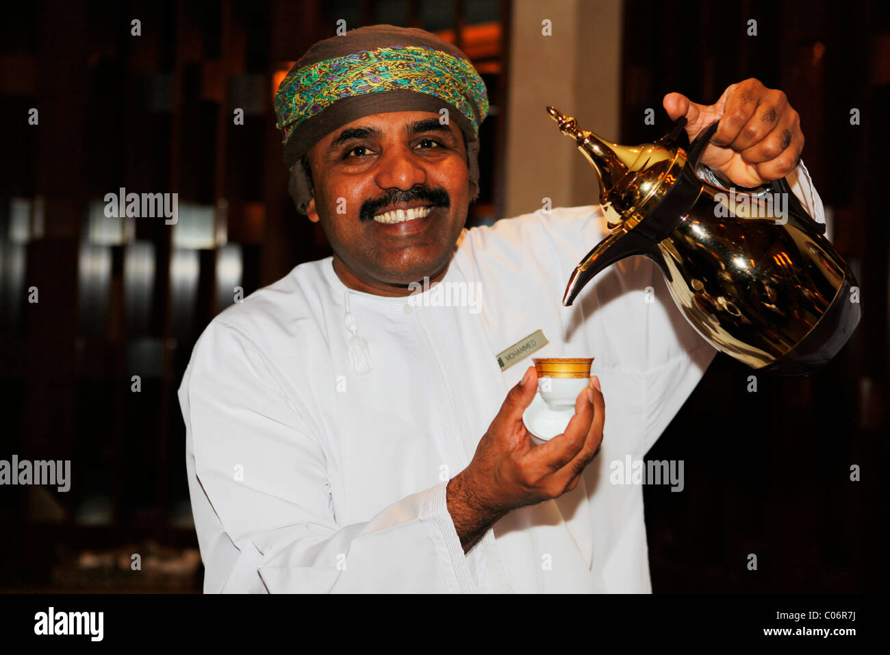 Ein omanischer Mann dient arabischen Kaffee aus einem Topf, bekannt als ein Dallah in Maskat, Oman. Stockfoto