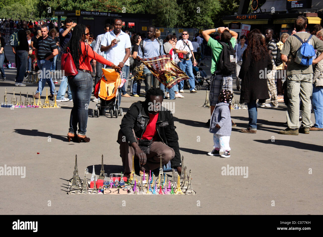 schwarzer afrikanischen Migranten Mann verkaufen Eiffel towers Souvenirs und Kuriositäten infront Eiffeltürmen, Paris, Frankreich Stockfoto