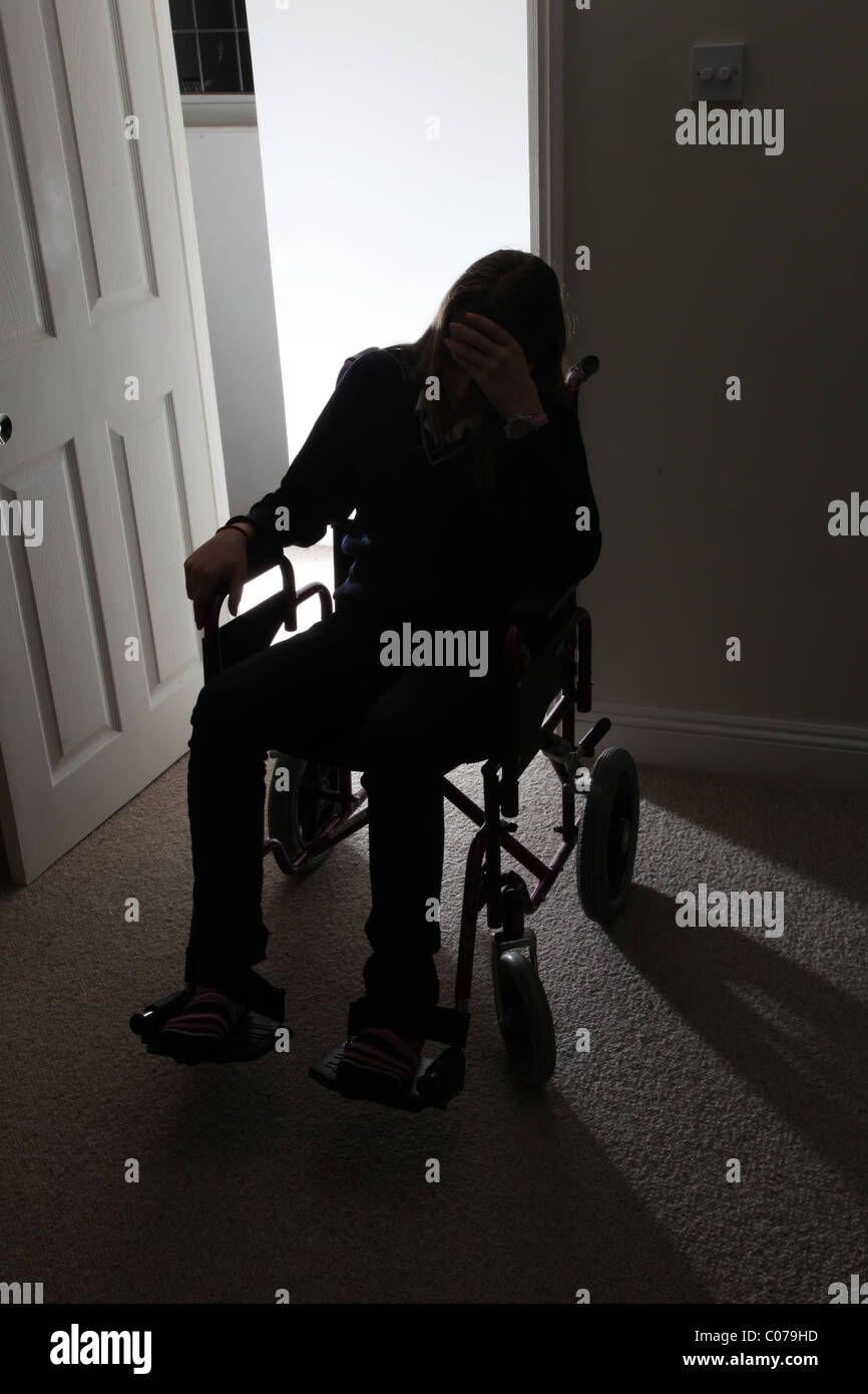 Mann im Rollstuhl, allein in einem dunklen Raum sitzen. Stockfoto