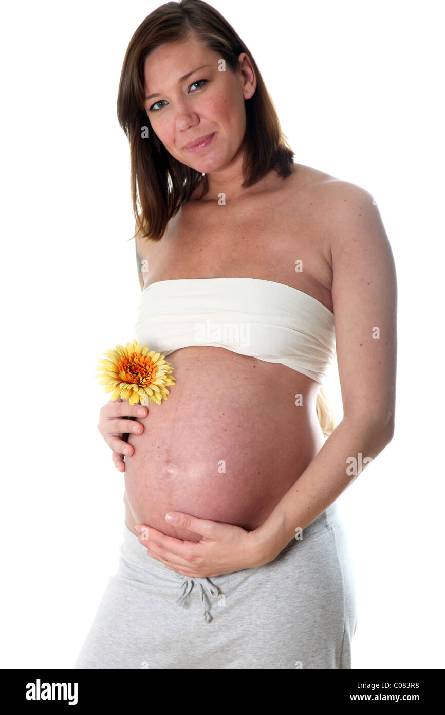 Lächelnd, hochschwangere Frau mit Babybauch in die Kamera schaut und hält eine Blume in Ihrem Bauch Stockfoto