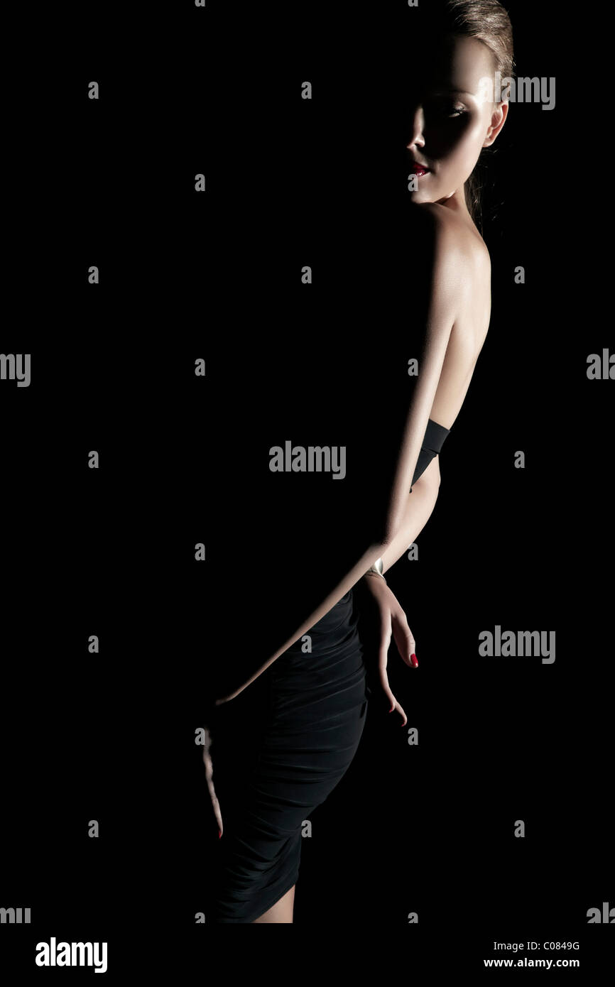 Junge Frau im schwarzen Kleid in Licht und Schatten Stockfoto