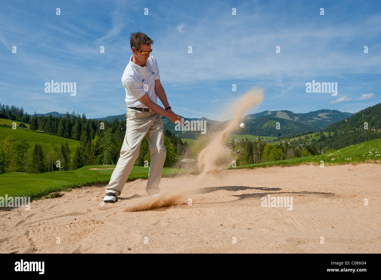 Golf-Spieler stehen in den Bunker zu zucken den Golfball aus dem Sand auf alpiner Golfplatz, Achenkirch, Tirol, Österreich Stockfoto