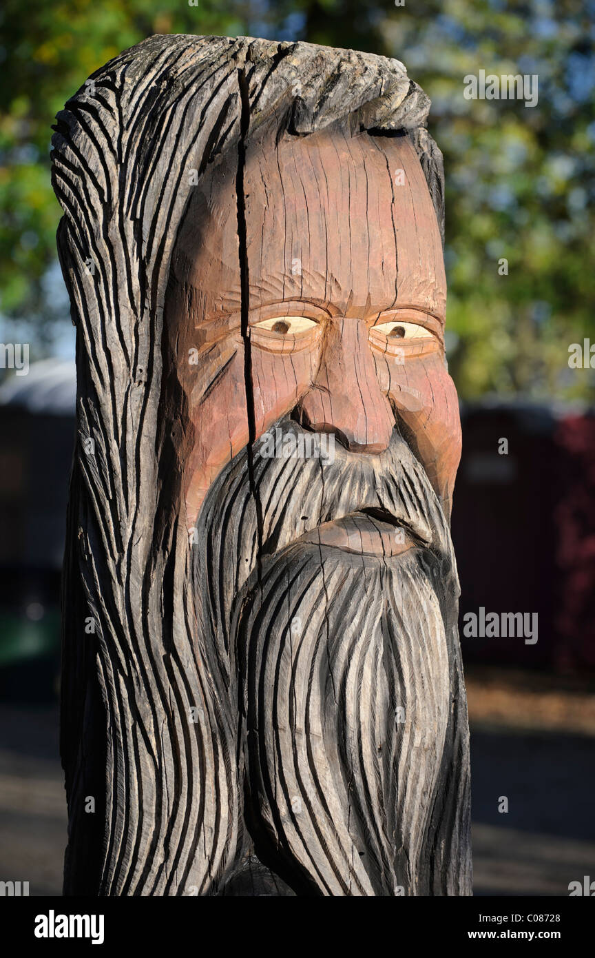 Bärtigen alten Mann Holzschnitzerei aus einem alten Baum, Leiter hautnah mit eindringlichen unheimlich starren, abgenutzt und verwitterte Statue. Stockfoto