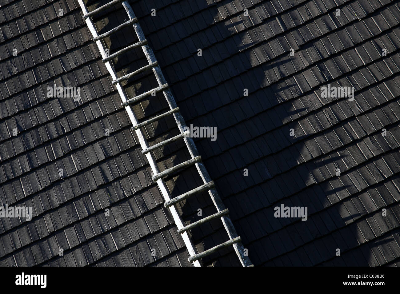 Schwarzen Schindeldach mit Holzleiter. Stockfoto