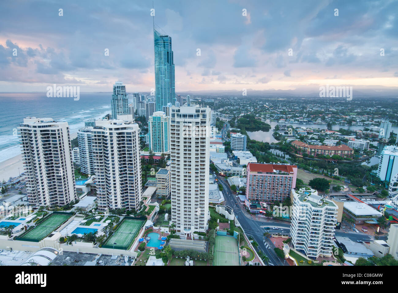 Moderne Stadt in der Dämmerung mit Ozean neben Stockfoto