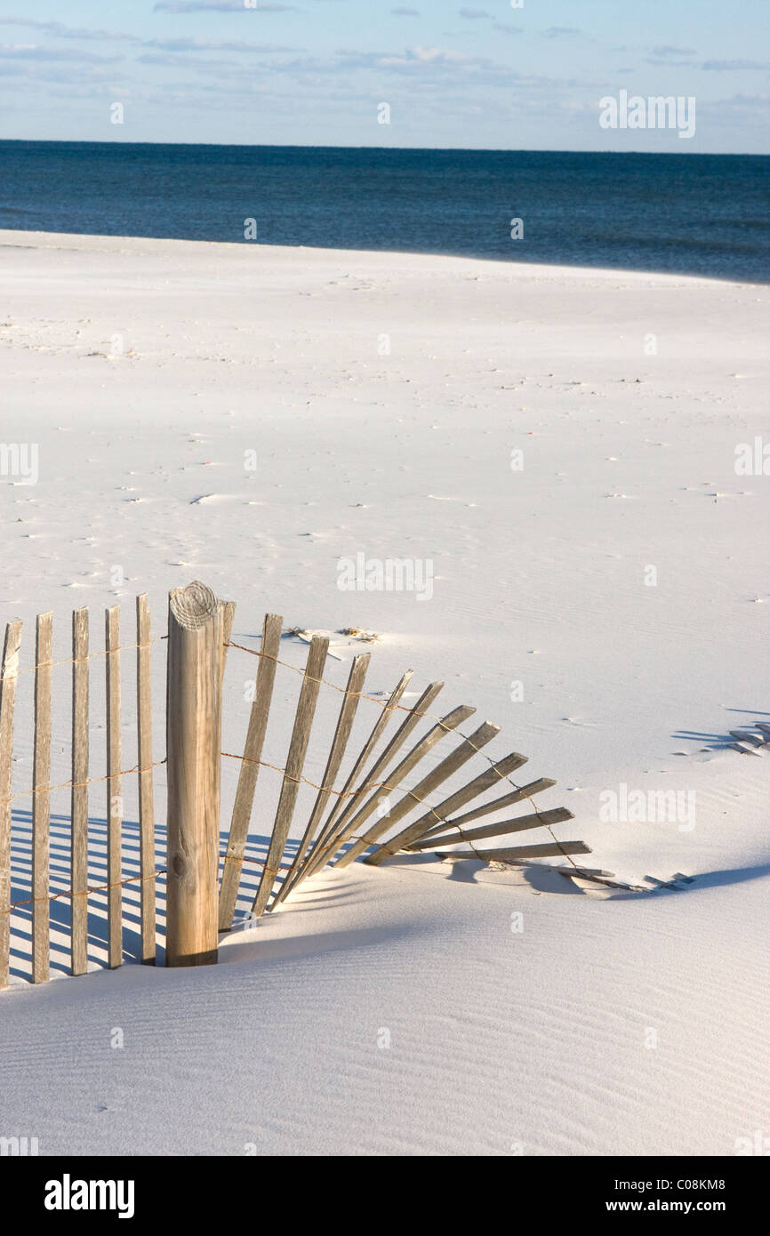 Ein Sandfence ist umgeweht und teilweise von Sand am Strand. Stockfoto