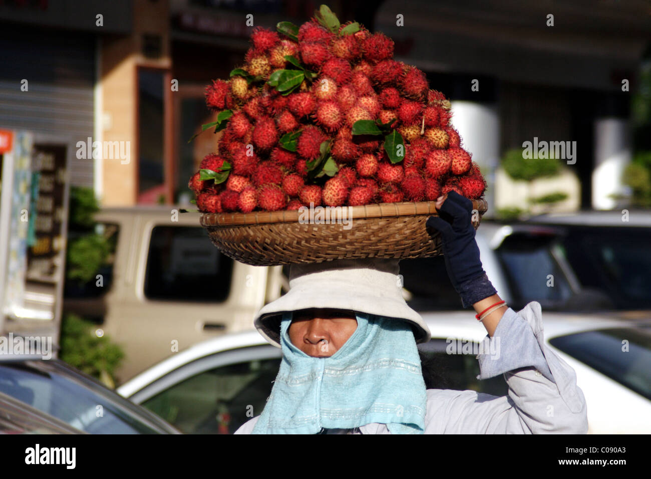 Eine Frau Essen Verkäufer trägt ein Tablett mit Obst auf ihrem Kopf nahe dem Zentralmarkt in Phnom Penh, Kambodscha. Stockfoto