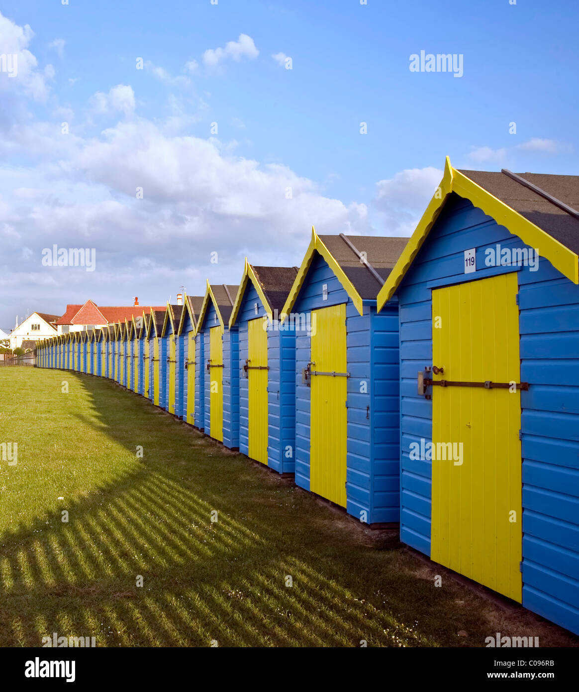 Schöne frische und lebendige bunte Bild der blauen und gelben Strandhütten aufgereiht entlang des Strandes in Chichester, England Stockfoto
