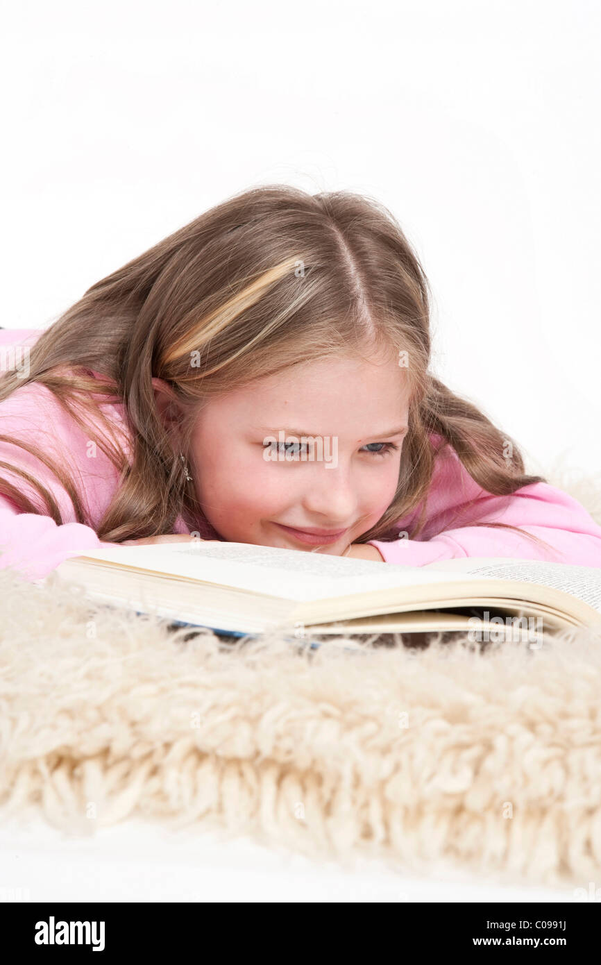 Mädchen, 8 Jahre, auf ein Shag Teppich liegen und ein Buch zu lesen Stockfoto