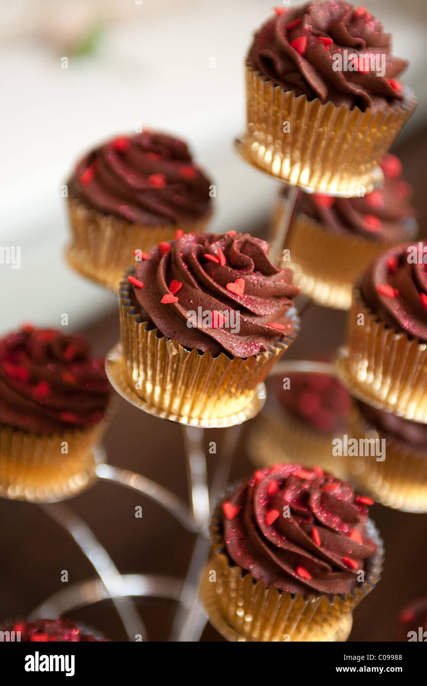 Chocolate Swirl Tasse Kuchen in Goldgehäusen auf einem Display-Ständer Stockfoto