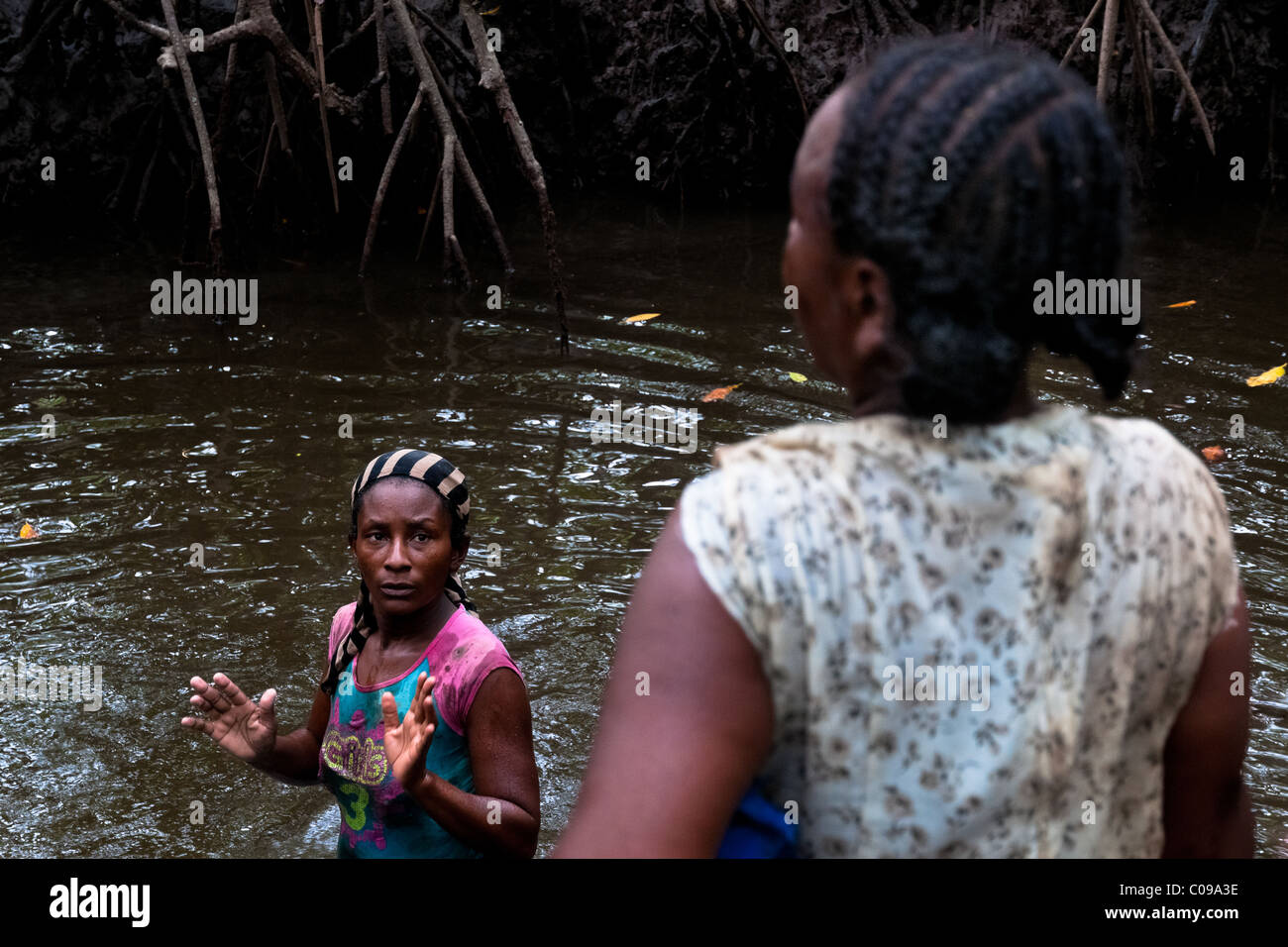 Kolumbianische Frauen waschen den Schlamm aus ihren Kleidern in das schmutzige Wasser der Mangrovensümpfe an der Pazifikküste, Kolumbien. Stockfoto