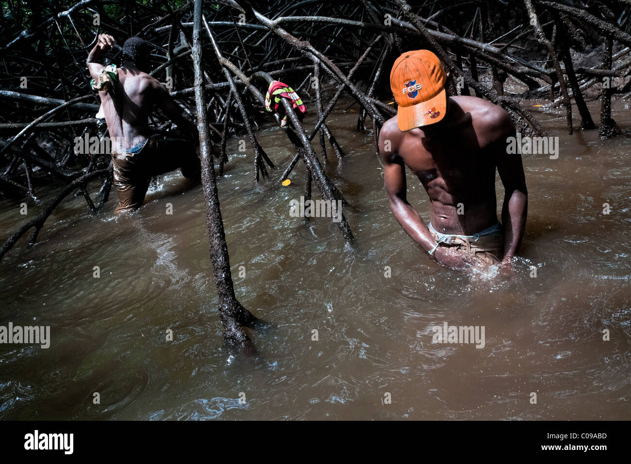 Kolumbianische jungen waschen den Schlamm aus ihren Kleidern in das schmutzige Wasser der Mangrovensümpfe an der Pazifikküste, Kolumbien. Stockfoto