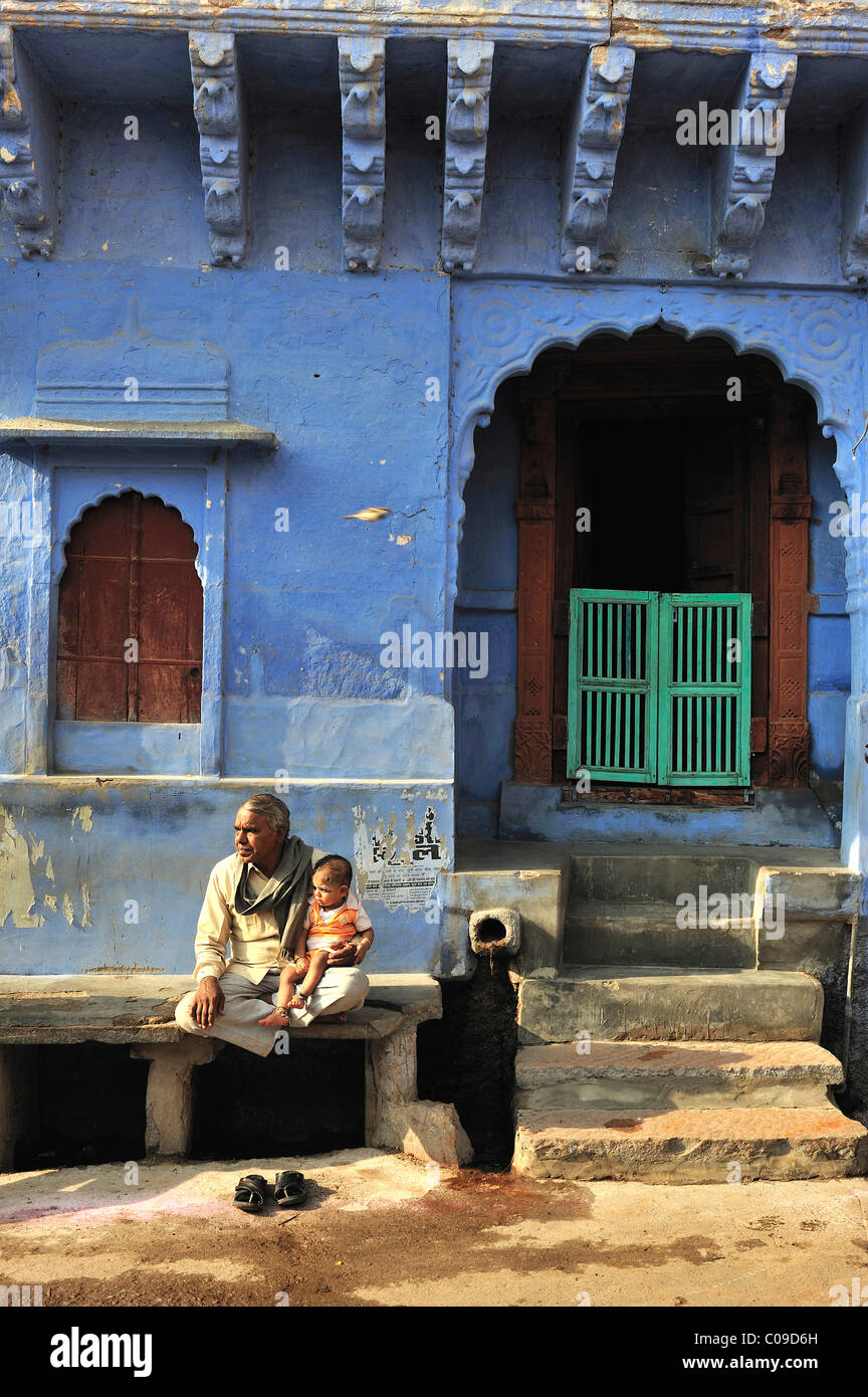 Älterer Mann mit einem Kind auf Steinbank vor seinem Haus, Jodhpur, Rajasthan, Indien, Asien Stockfoto