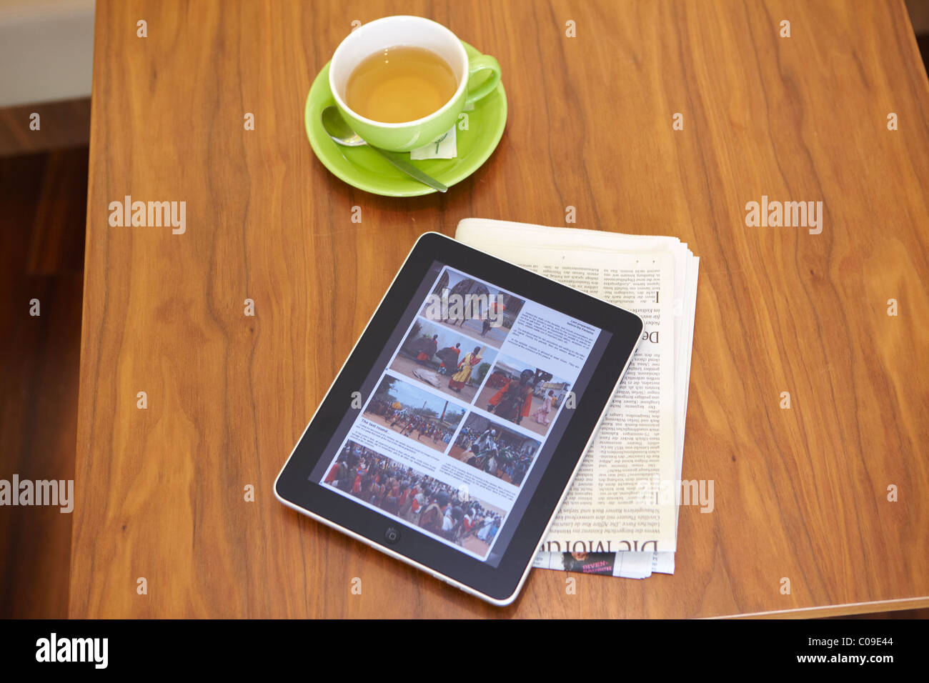IPad Tablet-Computer mit einem Wasserglas und einer Zeitung auf einem Holztisch Stockfoto