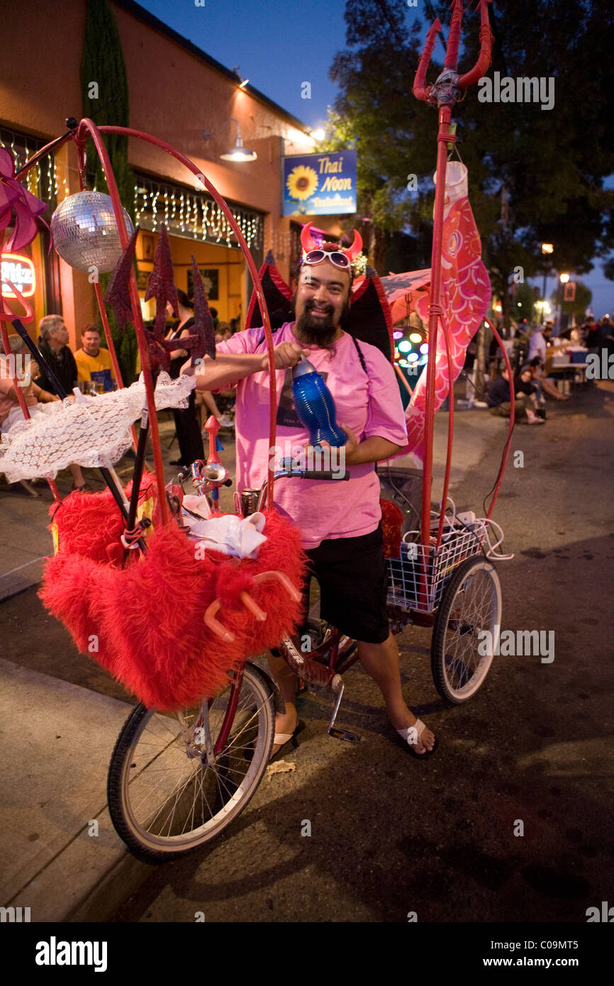 Mann verkleidet als Teufel Posen mit geschmückten Fahrrad. Stockfoto
