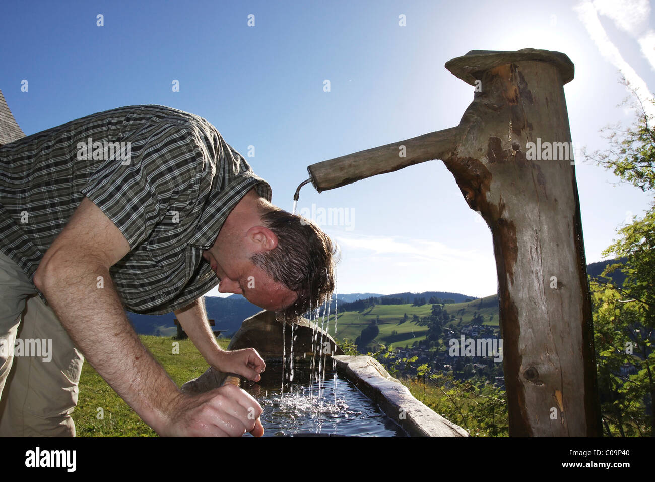 Ein Mann in seiner Mitte der 40er Jahre kühlt sich an einem Brunnen, Todtnauberg im Schwarzwald, Baden-Württemberg, Deutschland, Europa Stockfoto