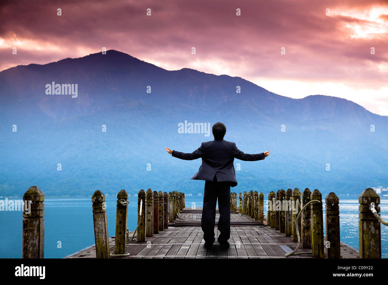 Geschäftsmann Stand am Pier und beobachtete die Berg und Wolke von sunrise Stockfoto