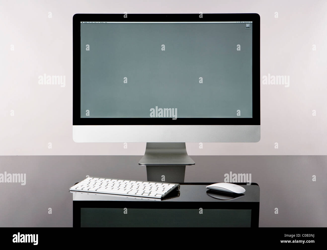 moderne drahtlose Computer mit Tastatur und Maus, isoliert auf einen Glasschreibtisch mit grauem Hintergrund, Vorderansicht grauen Bildschirm Stockfoto