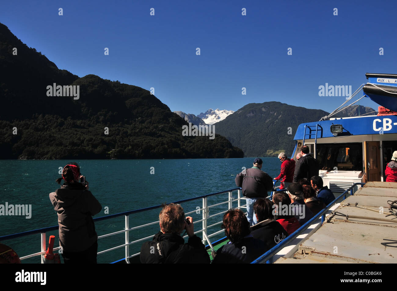 Blauer Himmelsblick auf Touristen mit Blick auf die weißen Gipfel des Volcan Tronador von einem Katamaran auf See Todos Los Santos, Brasilien Stockfoto