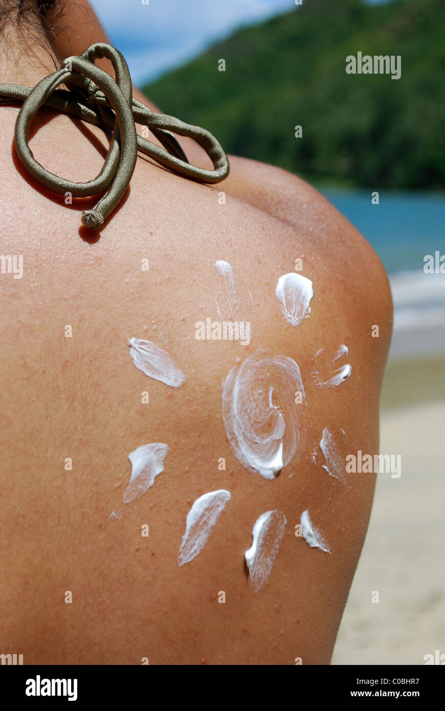 Sonnenschutz Sonne. Frau am Strand im Badeanzug mit Sonne in Sonnencreme auf Schulter gezeichnet. Oahu Hawaii. Stockfoto