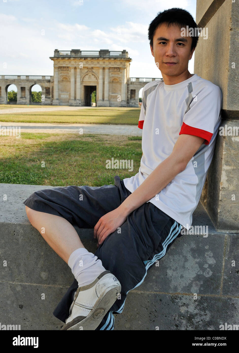 Paris, Frankreich, Portrait junger Chinese, Student sitzt vor dem Schloss, porträts aus china Stockfoto