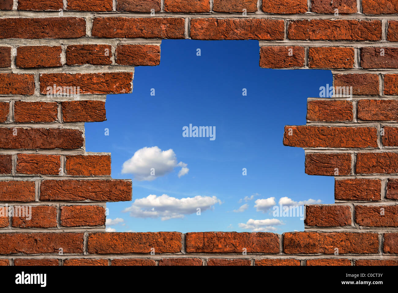 Blauer Himmel durch ein Loch in das Brickwall gesehen Stockfoto